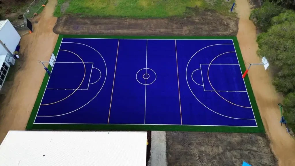 Close-up of synthetic grass and game line markings on a newly constructed sports court.